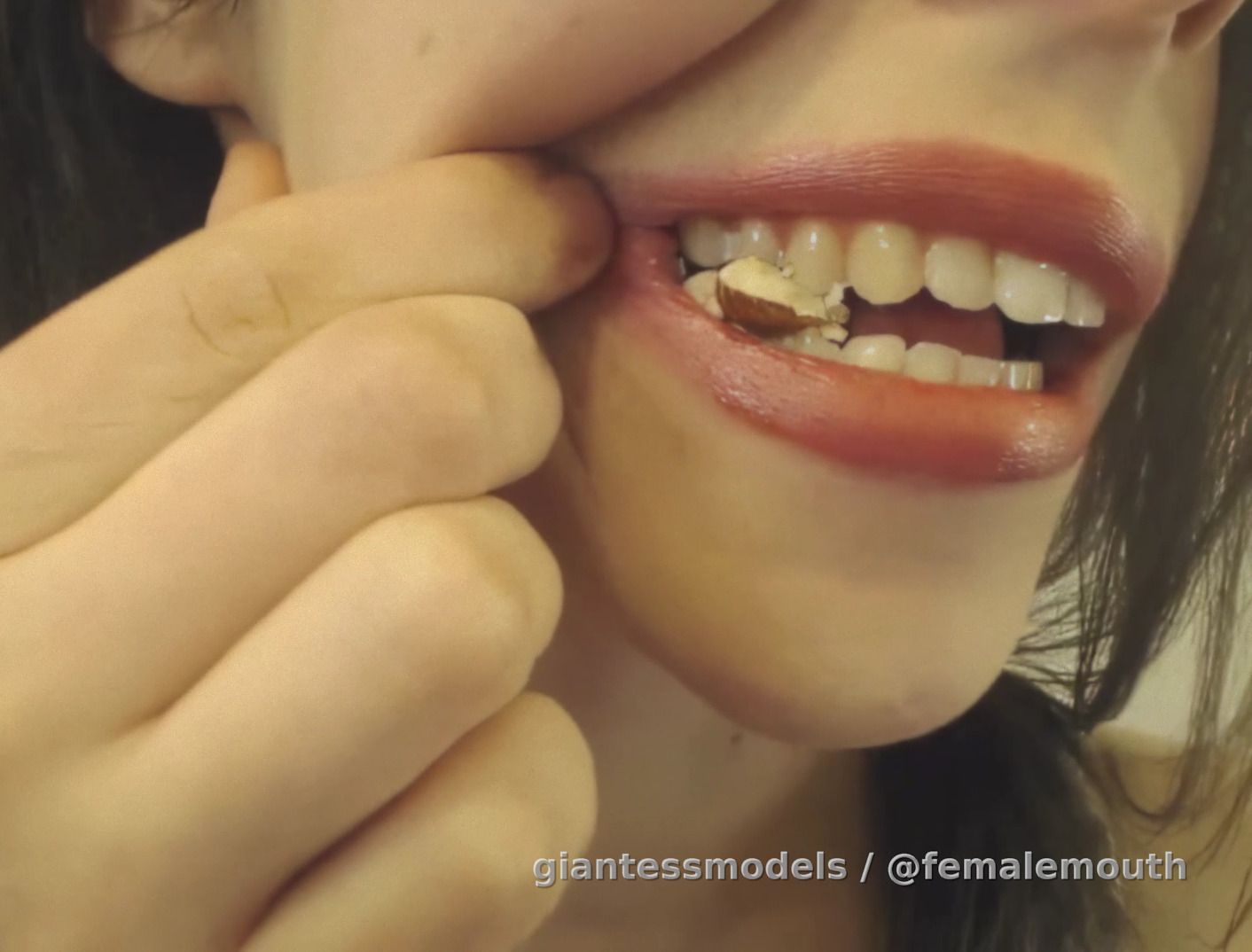 Pretty young female mouth crushes and chews almonds on a closeup. They doesn't even stand a chance! Almonds are hard, but guess what's harder!